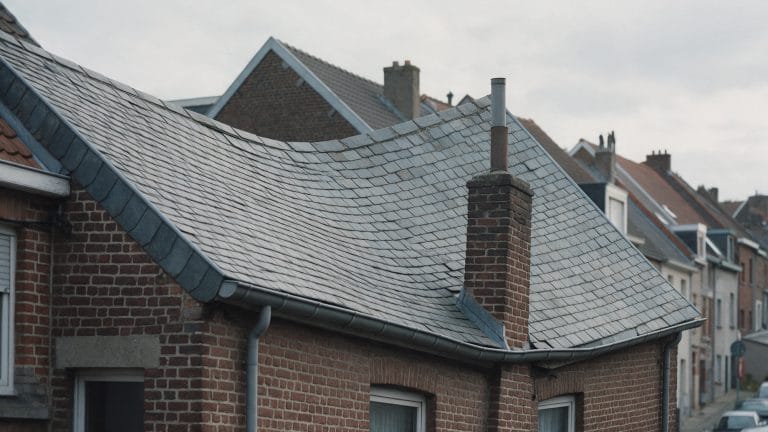 Ligne de faîtage ondulée sur une toiture en ardoise naturelle d'une maison de rang